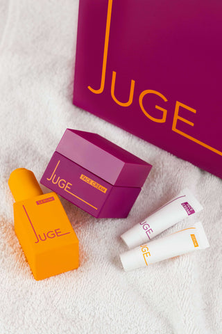 Close-up van JUGE Serum, Face Cream, samples en giftbag op handdoek